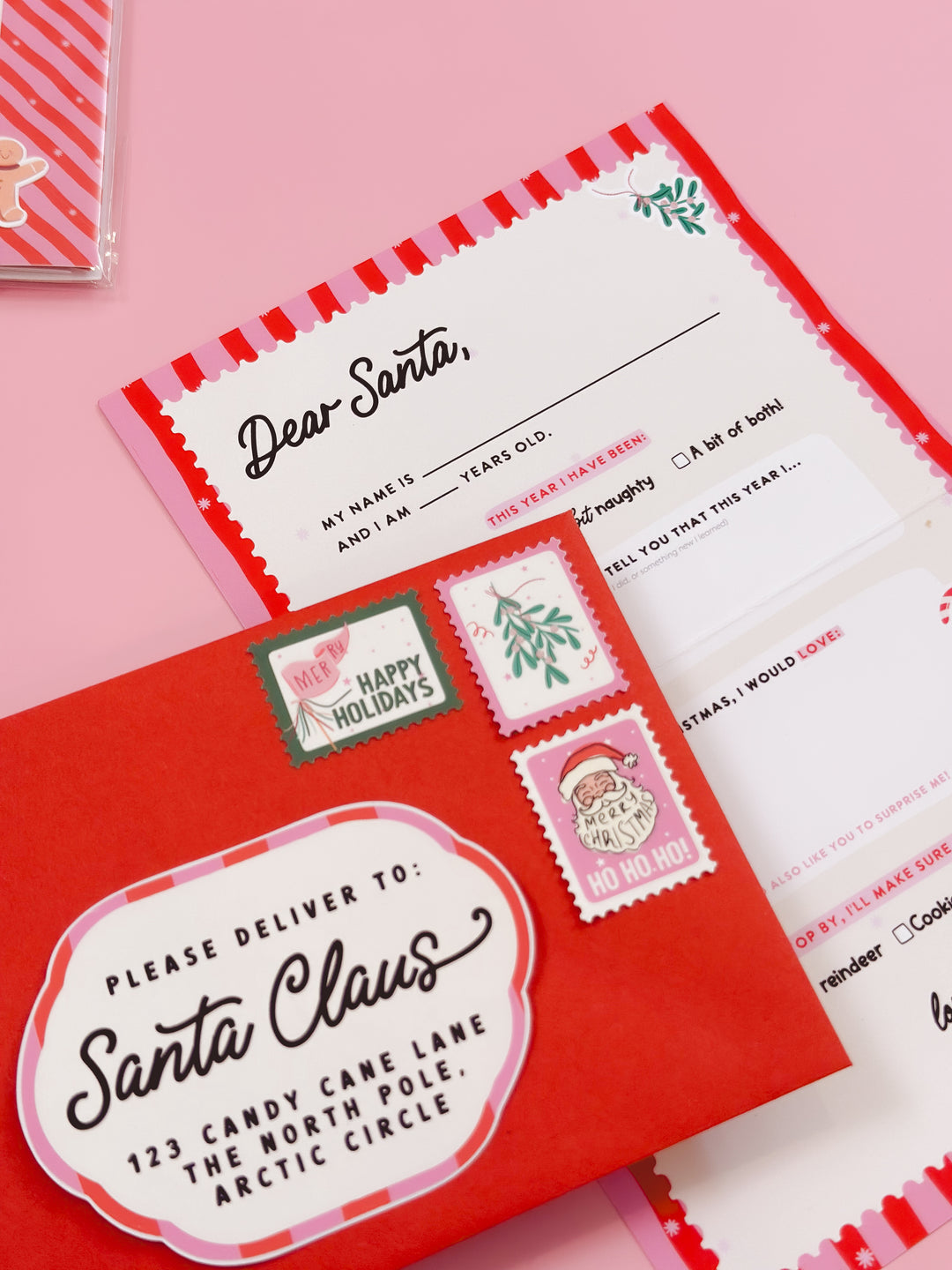 Letter to Santa Claus with red envelope on a pink background. Christmas letter writing kit showing stationery and North Pole envelope.