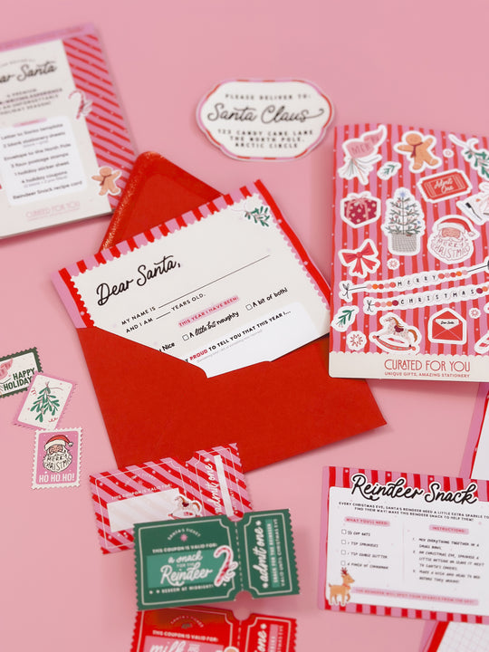 Set of Christmas-themed stationery items on a pink background
